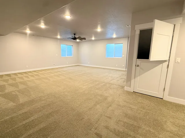Spacious room featuring neutral carpeting, recessed lighting, and a ceiling fan