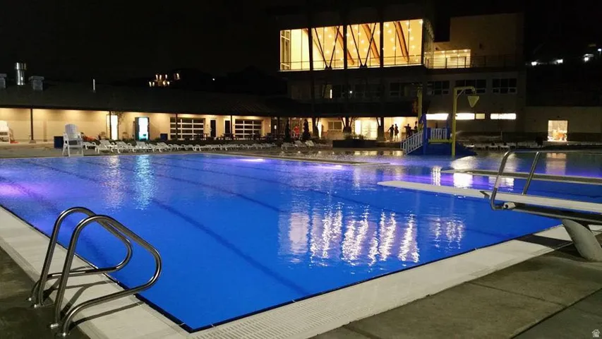 Community swimming pool featuring lane lines, stainless steel ladder, and diving board