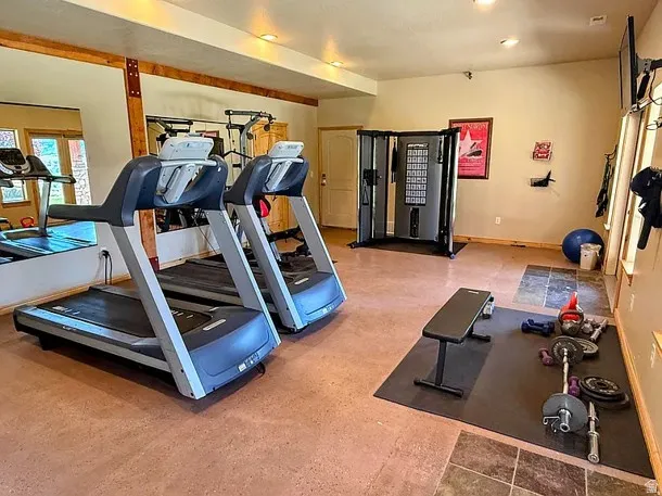 Dedicated fitness space featuring durable flooring, mirrored wall, and recessed lighting