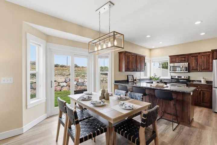 Open-concept dining area featuring wood-finish flooring, a contemporary linear chandelier, and access to the exterior through a glass sliding door