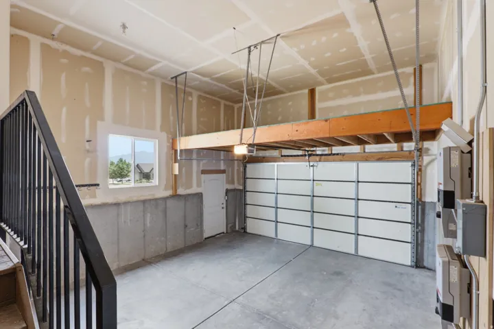 Spacious garage featuring a concrete floor, a multi-panel garage door, and an elevated storage platform
