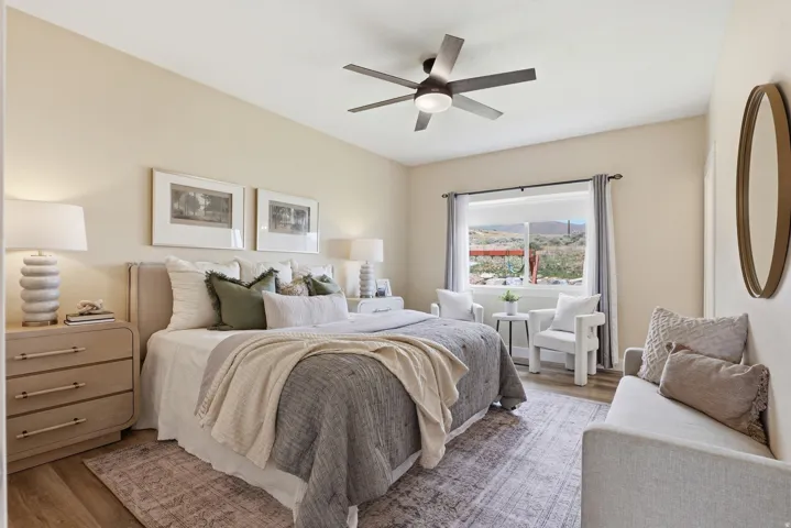 Bedroom featuring neutral wall tones, wood-finish flooring, a contemporary ceiling fan with integrated lighting, and a large window with a distant landscape