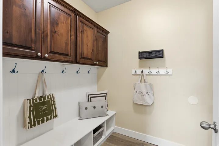 Built-in mudroom bench with cubby storage, wainscoting, and coat hooks