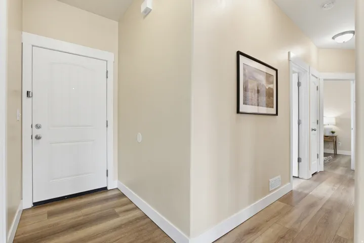 Entryway featuring wood-finish flooring, light-toned walls, white trim, and a paneled entry door with brushed nickel hardware