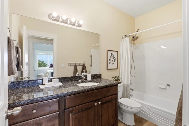 Bathroom featuring a dark wood vanity with a stone countertop, a drop-in sink, and a large wall mirror
