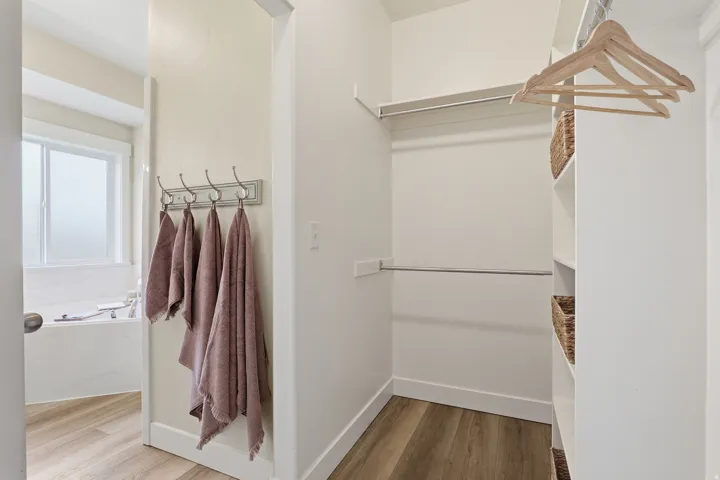 Walk-in closet with integrated shelving, dual hanging rods, and wood-finish flooring