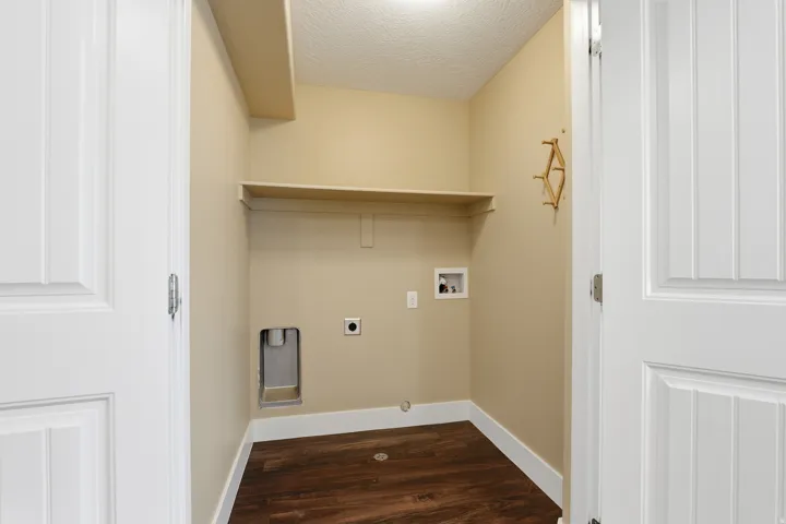 Dedicated laundry area featuring wood-finish flooring, light tan walls, and a built-in shelf
