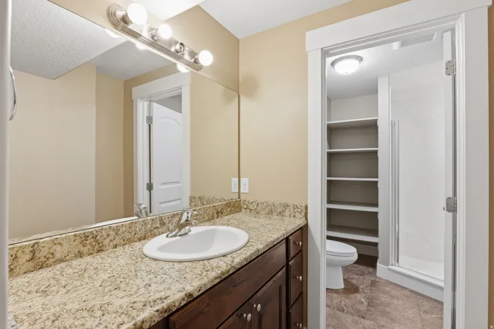 Bathroom vanity featuring a light granite countertop with an undermount sink