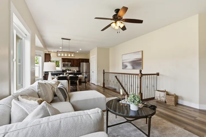 Open-concept living area with wood-finish flooring, a contemporary ceiling fan, and a wood and metal spindle railing