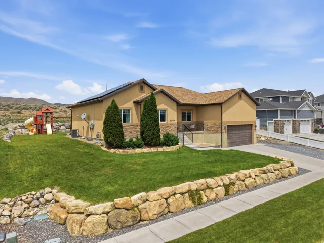 Contemporary stucco exterior featuring stone accents, a two-car garage, and a concrete driveway