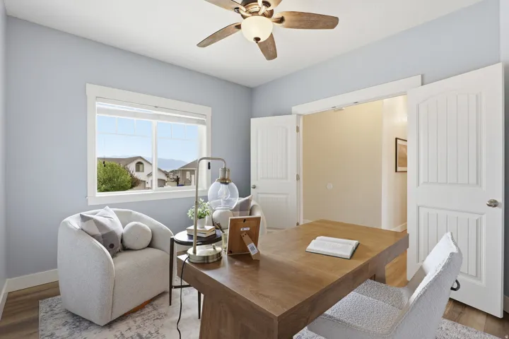 Spacious room featuring a ceiling fan with light fixture, large window with outdoor scenery, wood-finish flooring, and double paneled doors