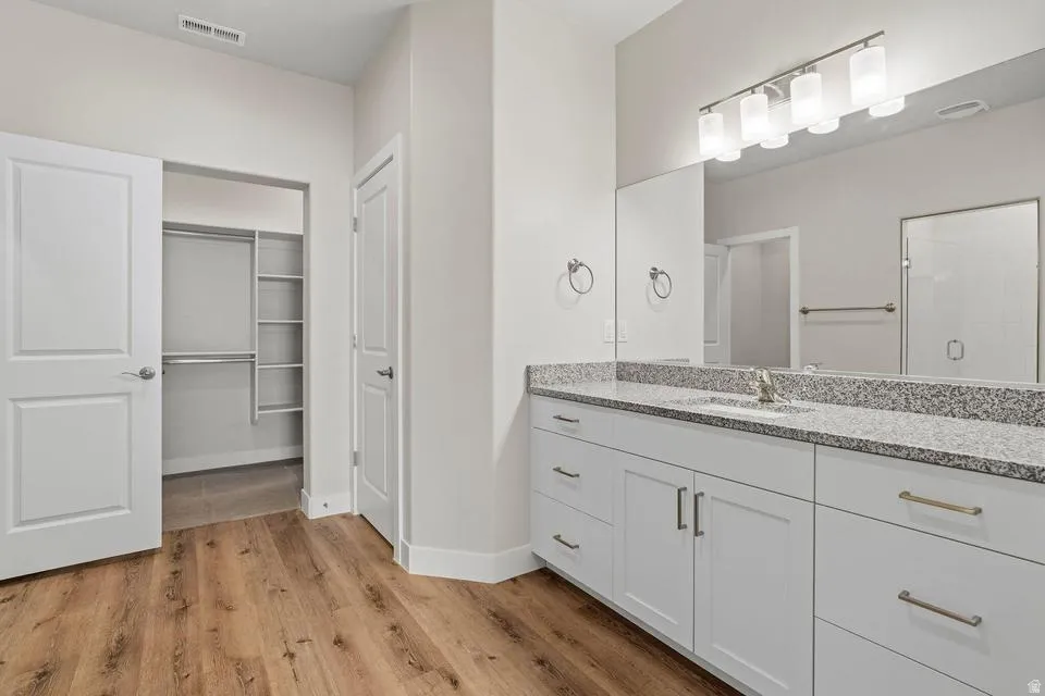 Vanity featuring a dual sink, stone-finish countertop, and integrated lighting