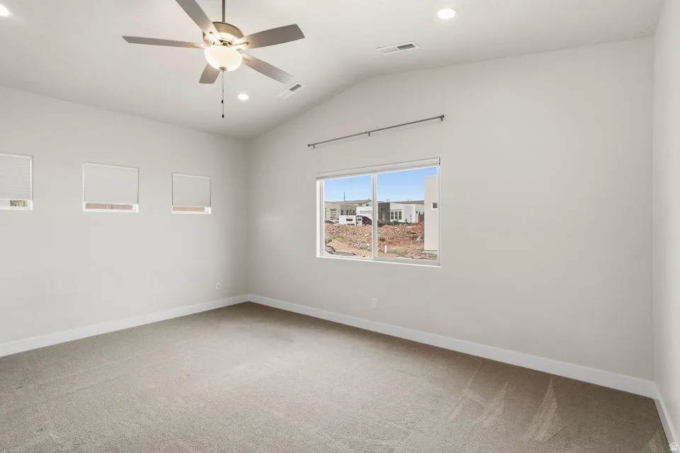 Vaulted ceiling room featuring carpet flooring and a ceiling fan with integrated lighting