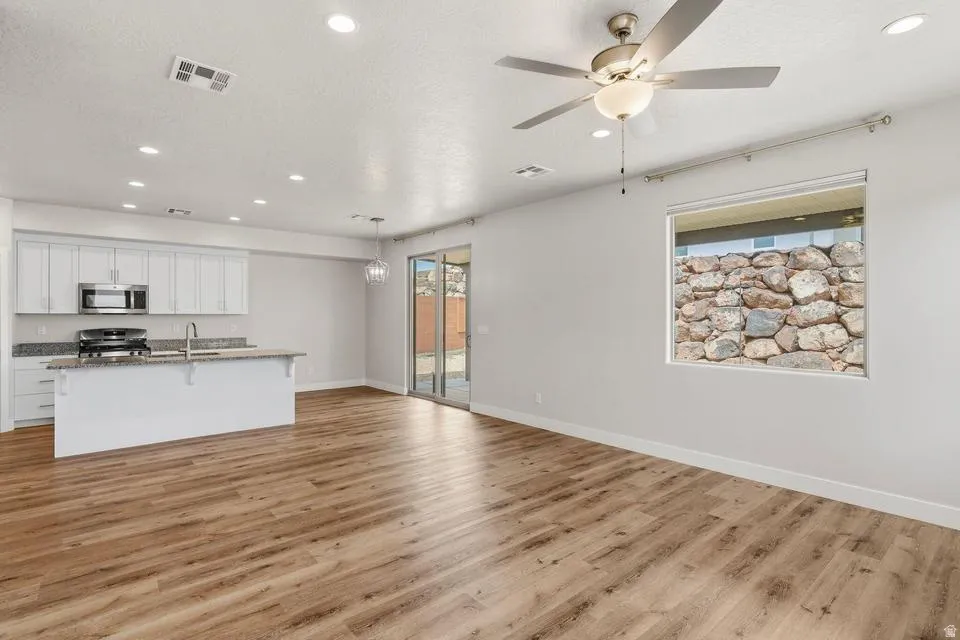 Open-concept living area featuring wood-finish flooring, recessed lighting, and a ceiling fan