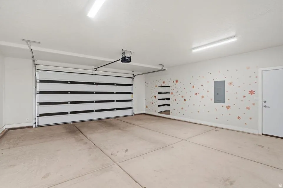 Spacious garage featuring a sectional overhead door with an automatic opener, concrete flooring, and built-in shelving