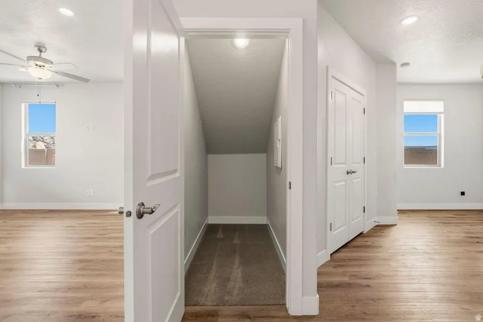 Hallway featuring wood-finish flooring, white walls, recessed lighting, and a closet with bifold doors