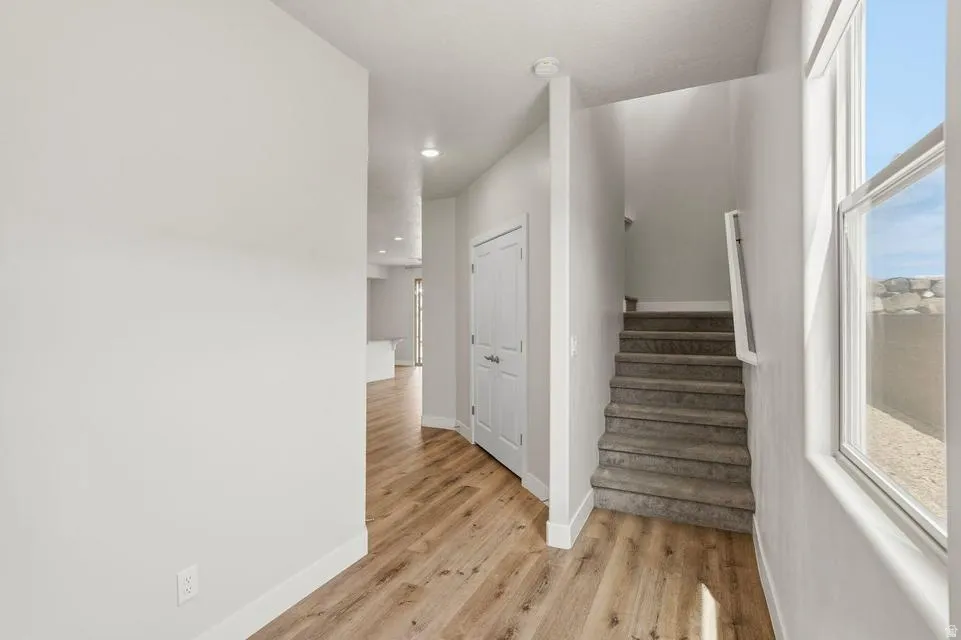 Entryway featuring wood-finish flooring, a carpeted staircase with a white handrail, a double-panel door, and recessed lighting