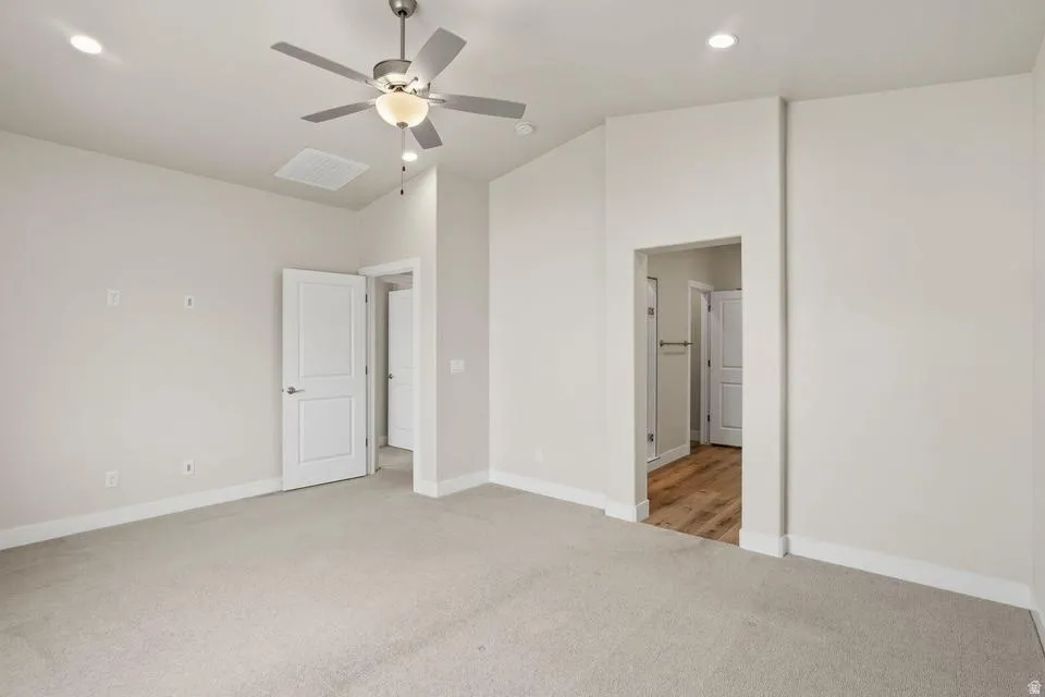 Spacious room featuring neutral carpeting, recessed lighting, a ceiling fan with light fixture, and white trim