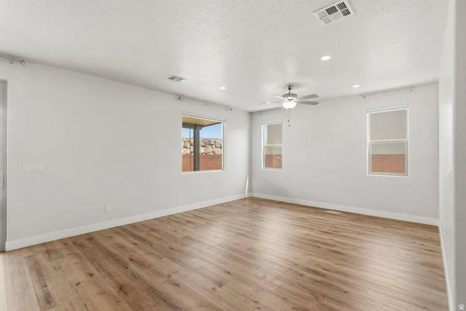 Spacious room featuring wood-finish flooring, white baseboards, and multiple windows