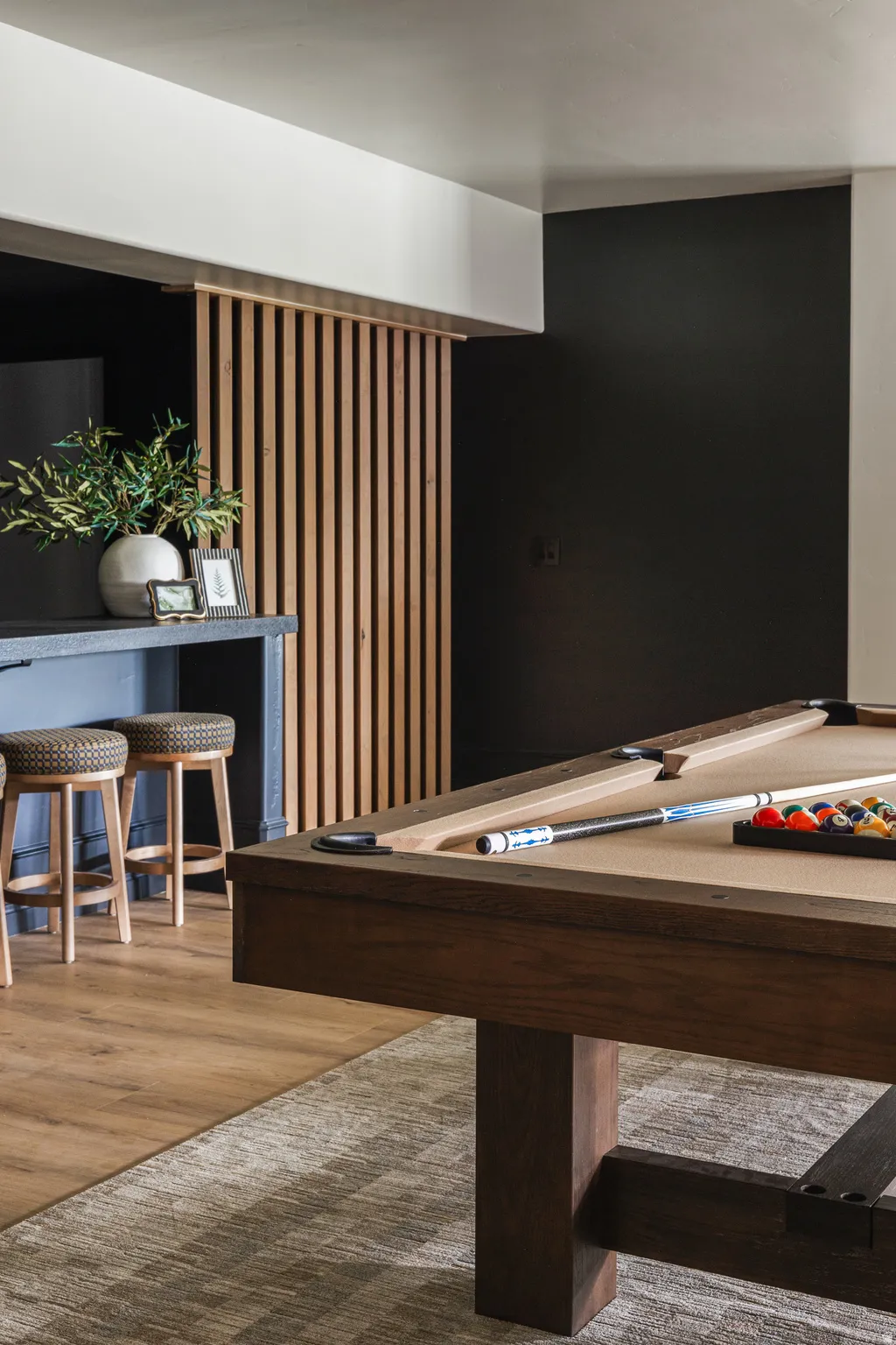 Entertainment area featuring wood-finish flooring, a wood-slat accent wall, and a built-in bar