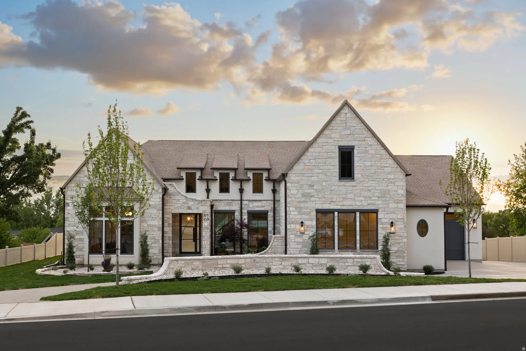 Stone exterior residence featuring a prominent gabled roofline, multiple dark-framed windows, and a black front entry door