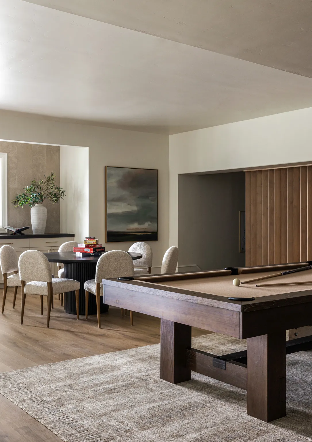 Recreation area featuring a solid wood billiards table, wood-finish flooring, and a recessed dining nook with built-in cabinetry and stone backsplash