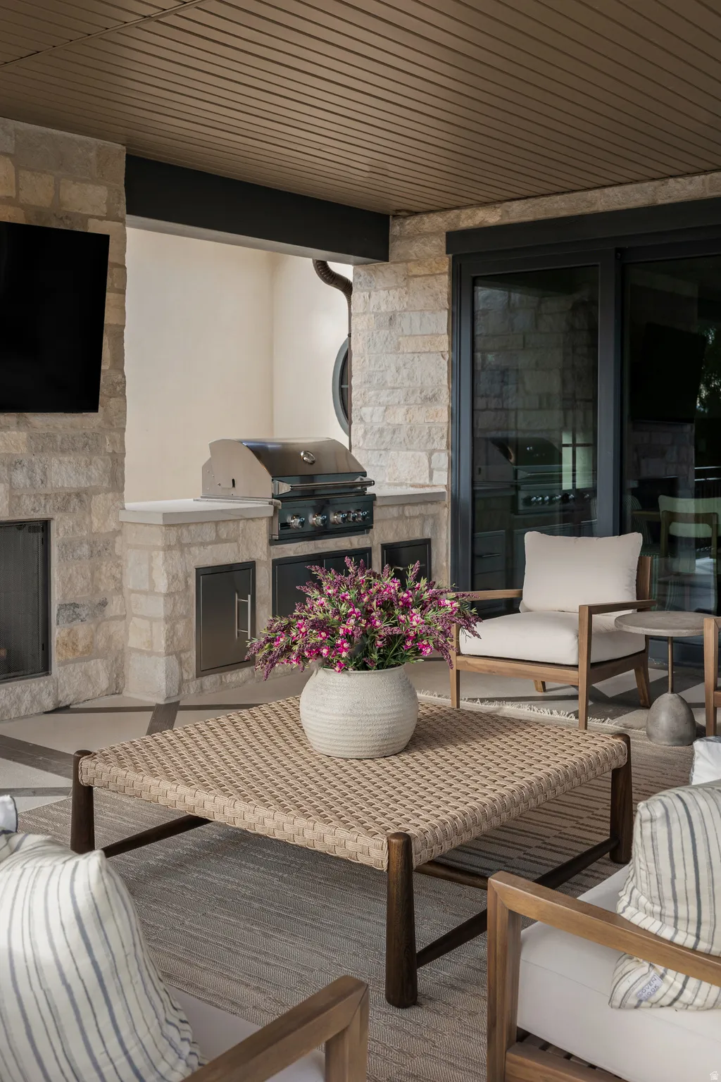 Covered patio featuring a built-in outdoor kitchen with grill, stone surround, and stainless steel cabinetry