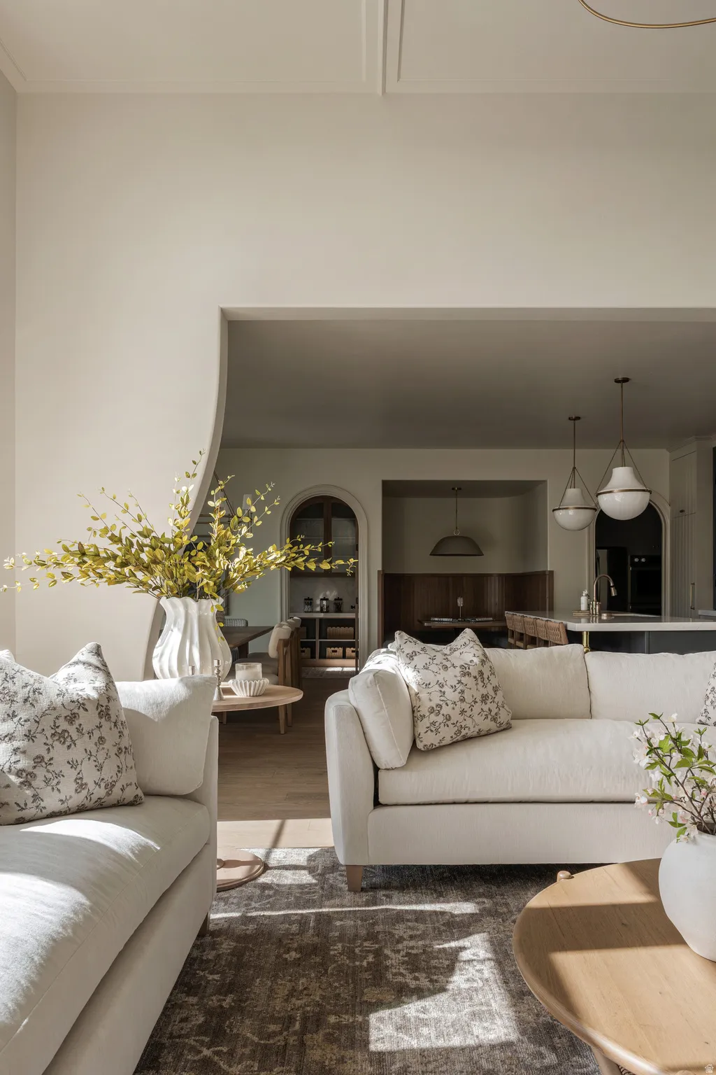 Arched entryway leading to an open-concept living area with wood-finish flooring, recessed lighting, and decorative pendant light fixtures
