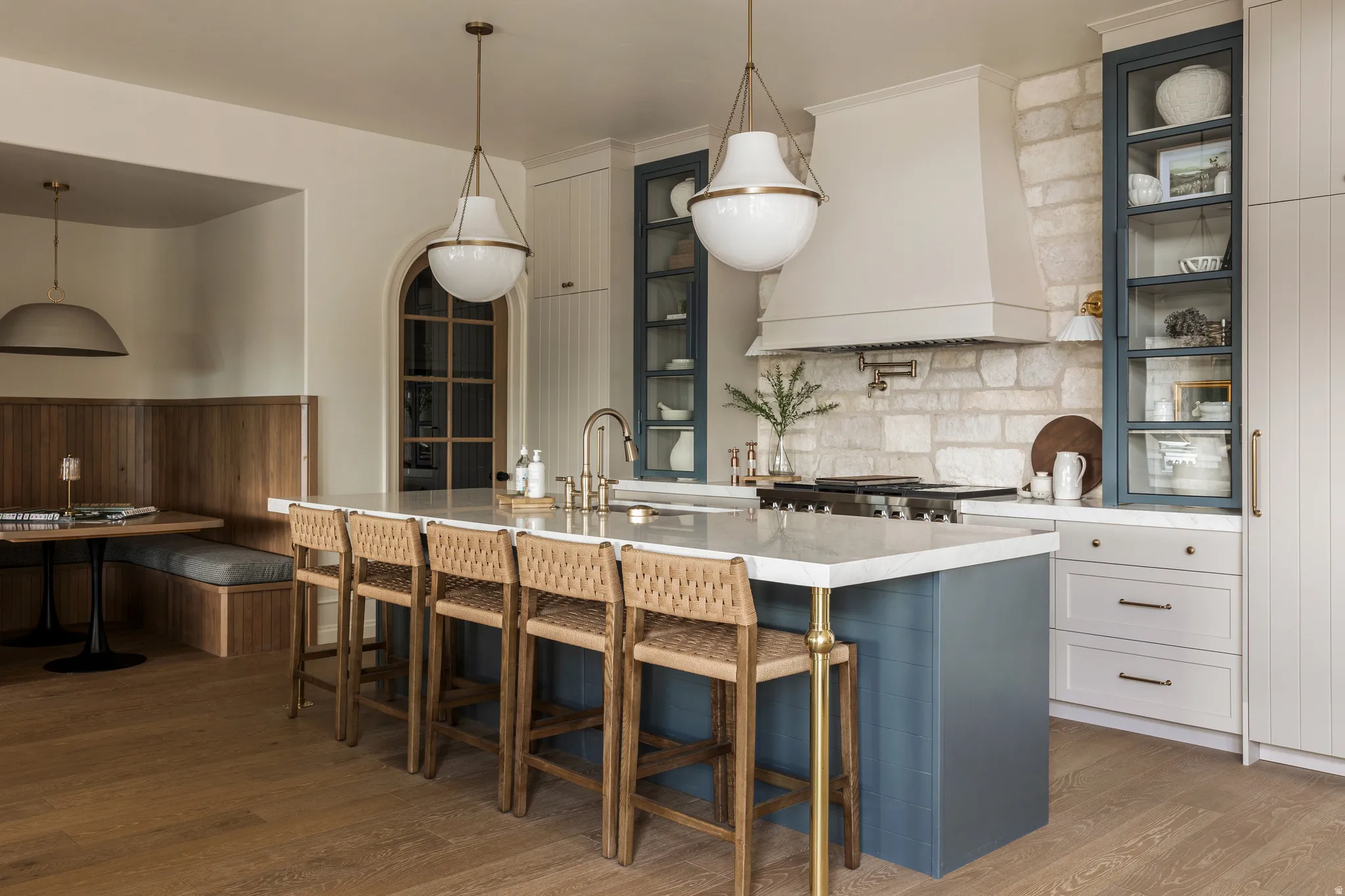 Gourmet kitchen featuring a substantial central island with seating, a stone accent wall, custom range hood, and integrated appliances