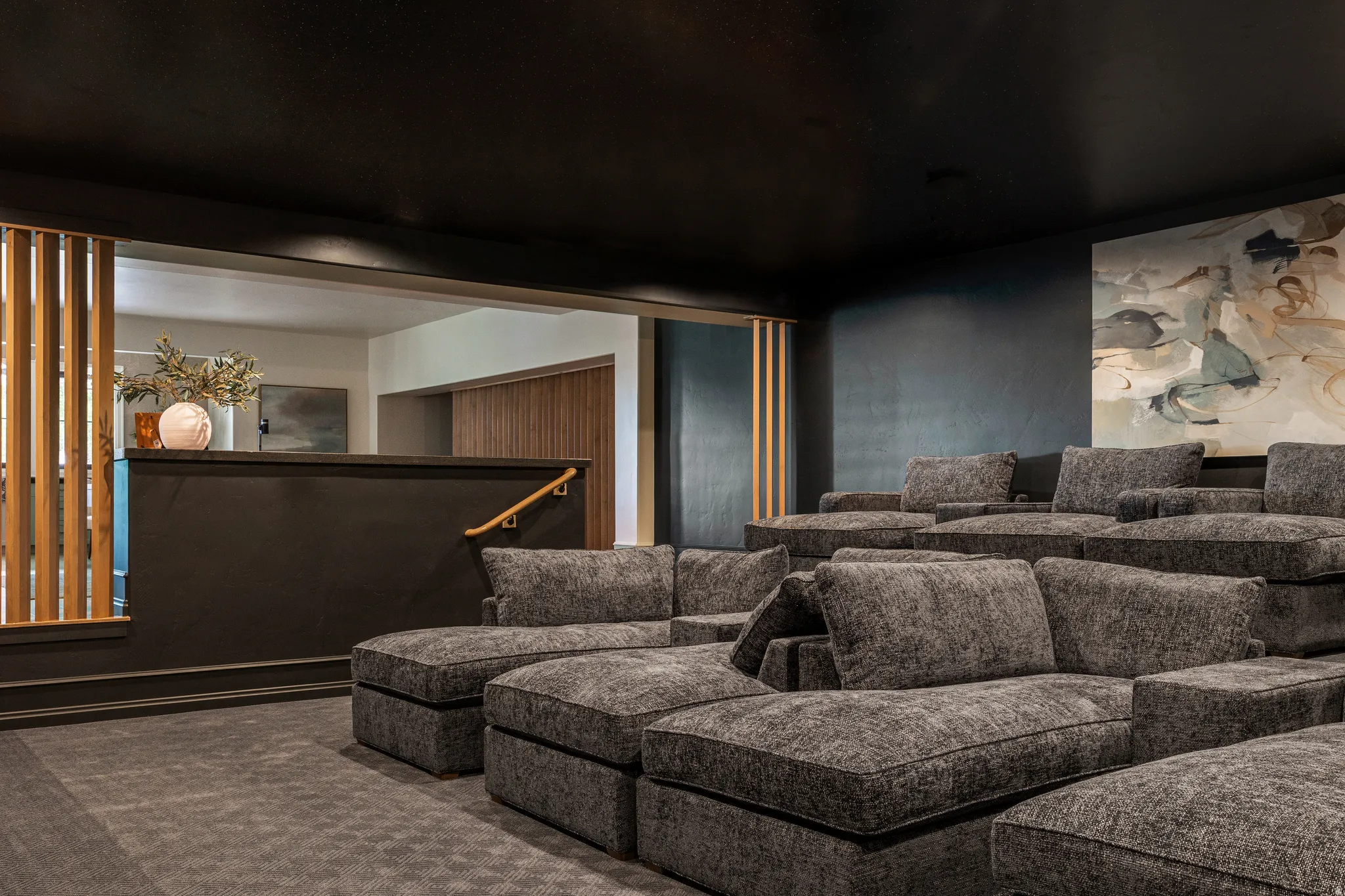 Tiered flooring in a media room with dark walls and ceiling