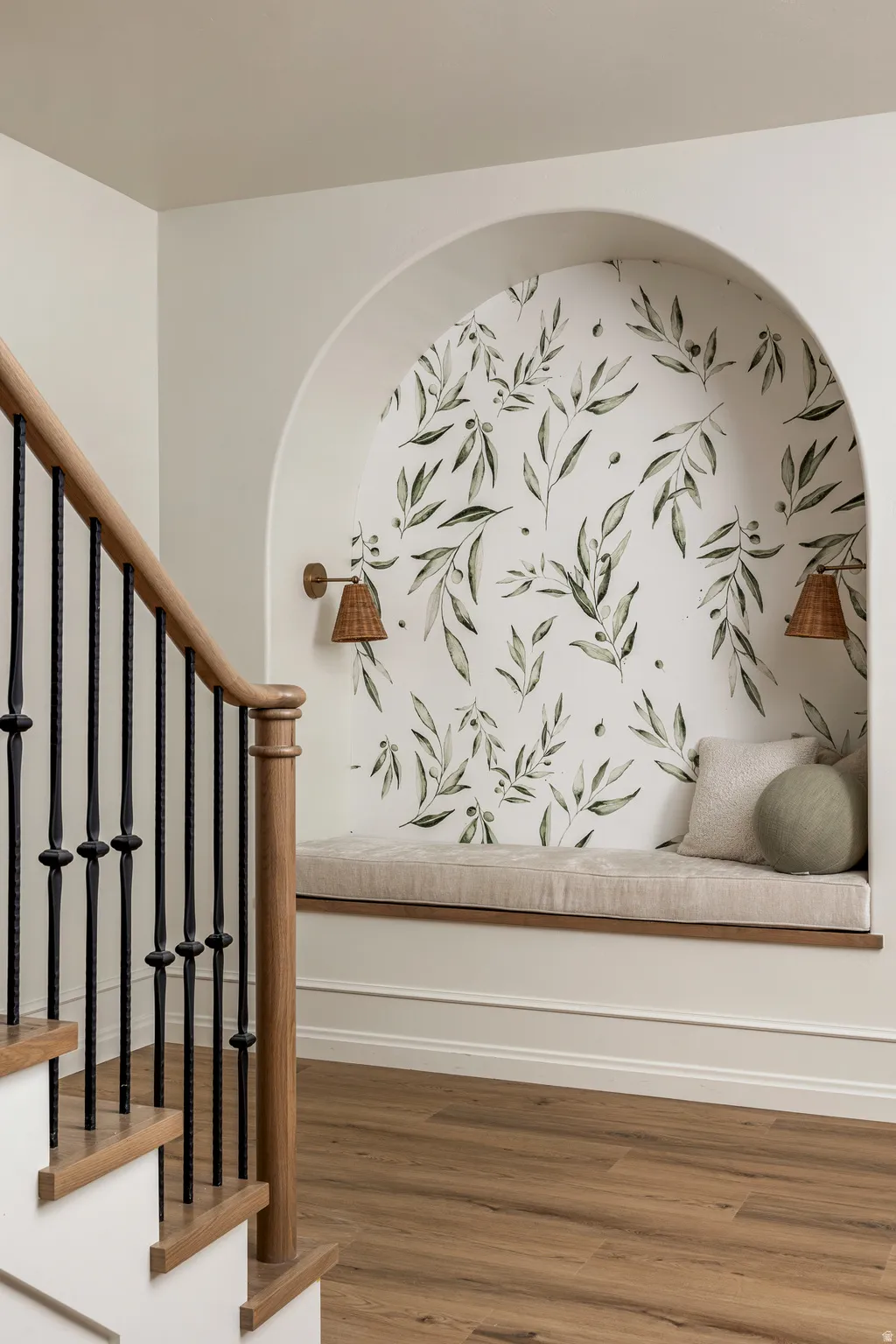 Built-in arched alcove featuring botanical wallpaper and a cushioned bench seat