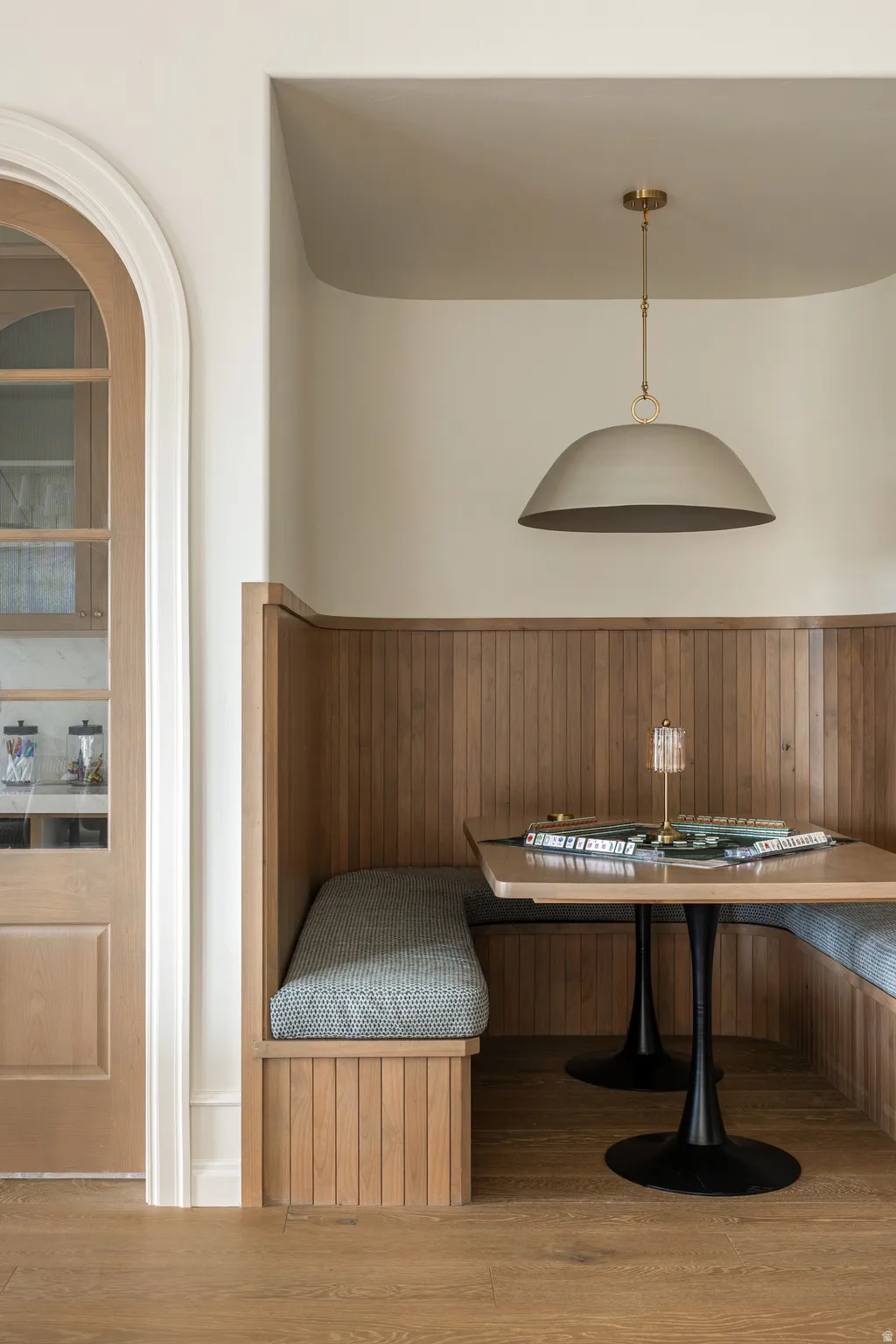 Built-in banquette seating with light wood paneling, upholstered cushions, and two pedestal tables