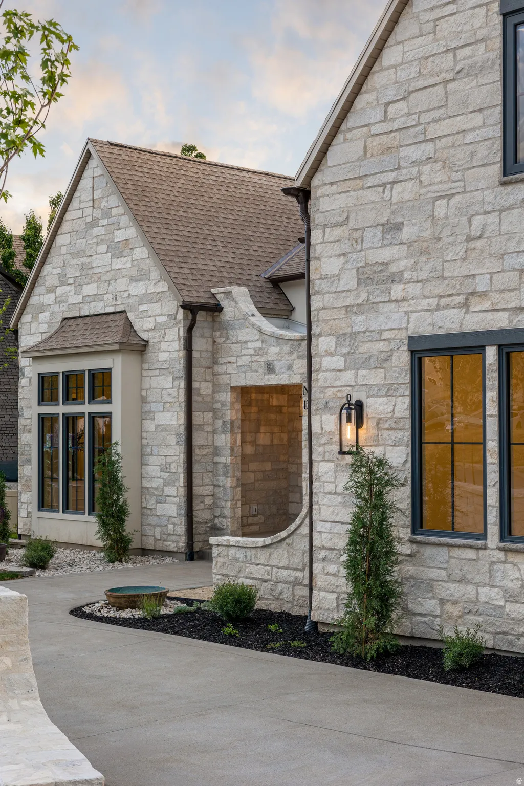 Stone facade exterior featuring dark-framed windows, a prominent gable roof, and a contemporary outdoor sconce