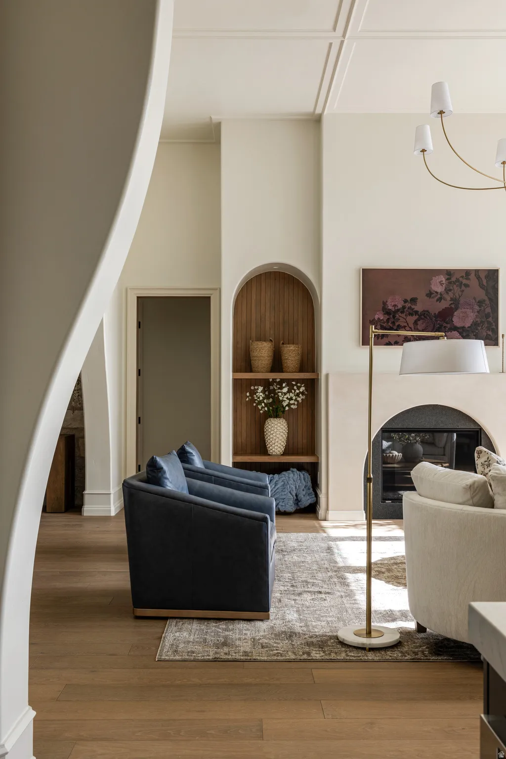 Spacious living area featuring wood-finish flooring, an arched built-in niche with shelving, and a coffered ceiling