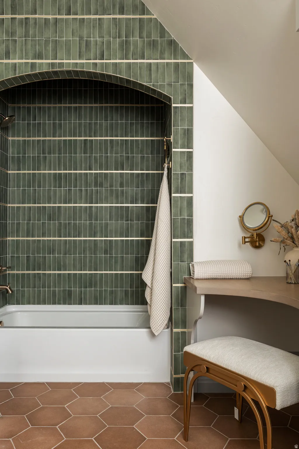 White bathtub with arched green tile surround