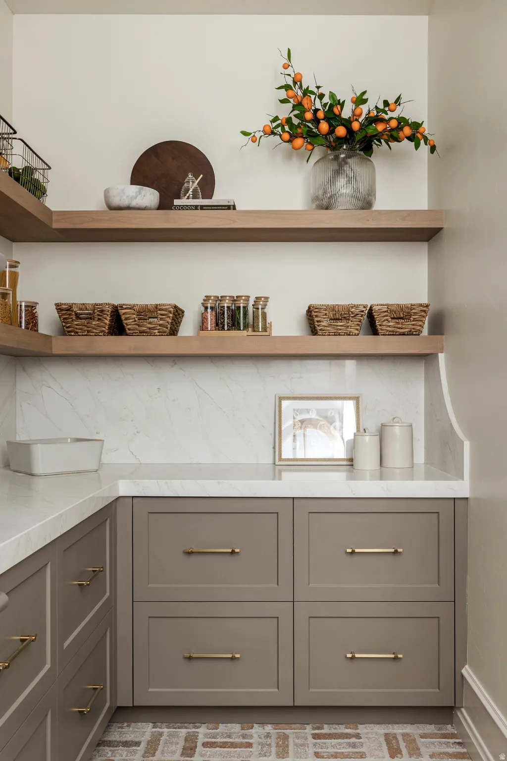Corner cabinet storage with shaker-style doors, brass hardware, and light-tone countertops