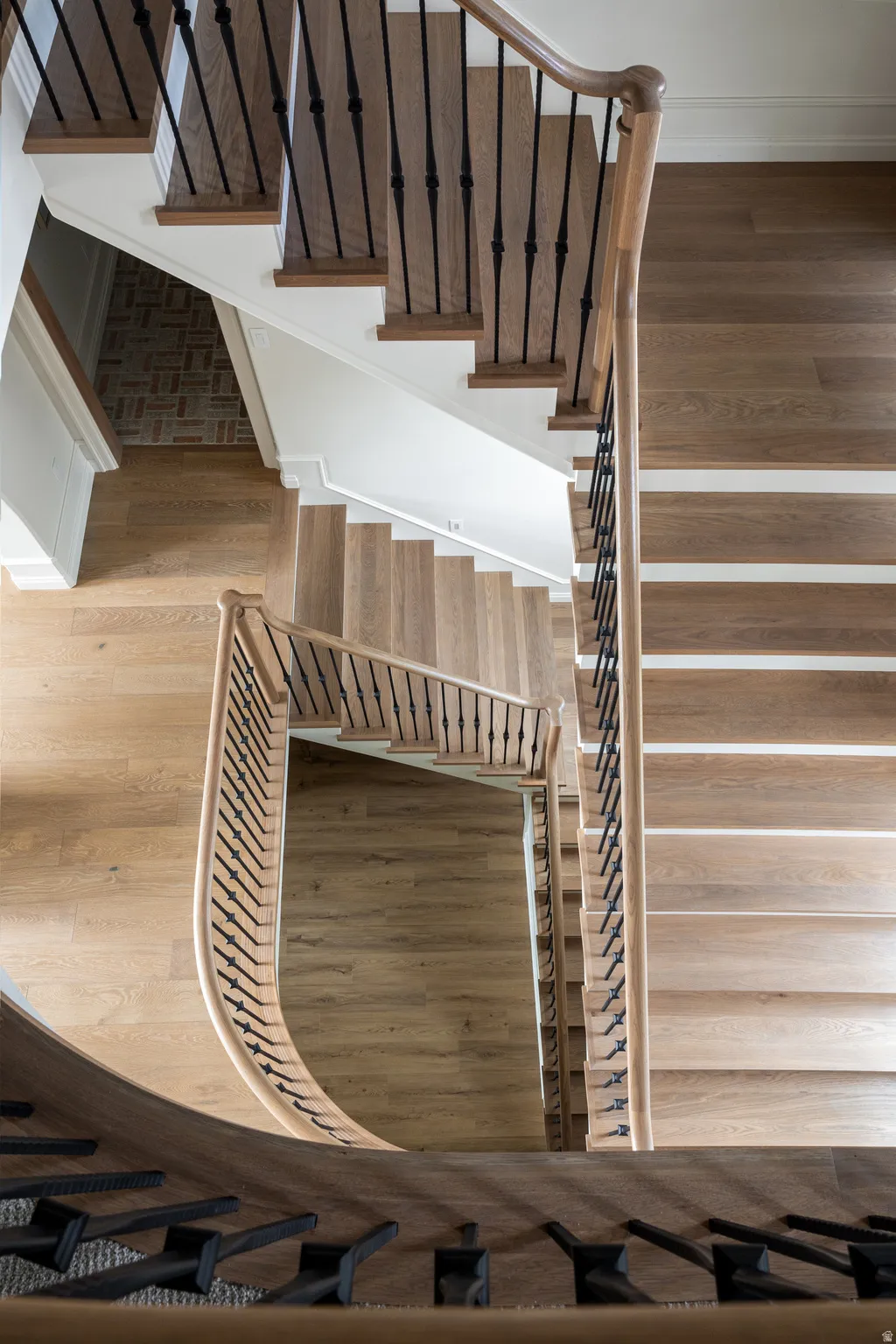 Grand multi-level staircase featuring light wood-finish flooring, white risers, and wrought iron balusters