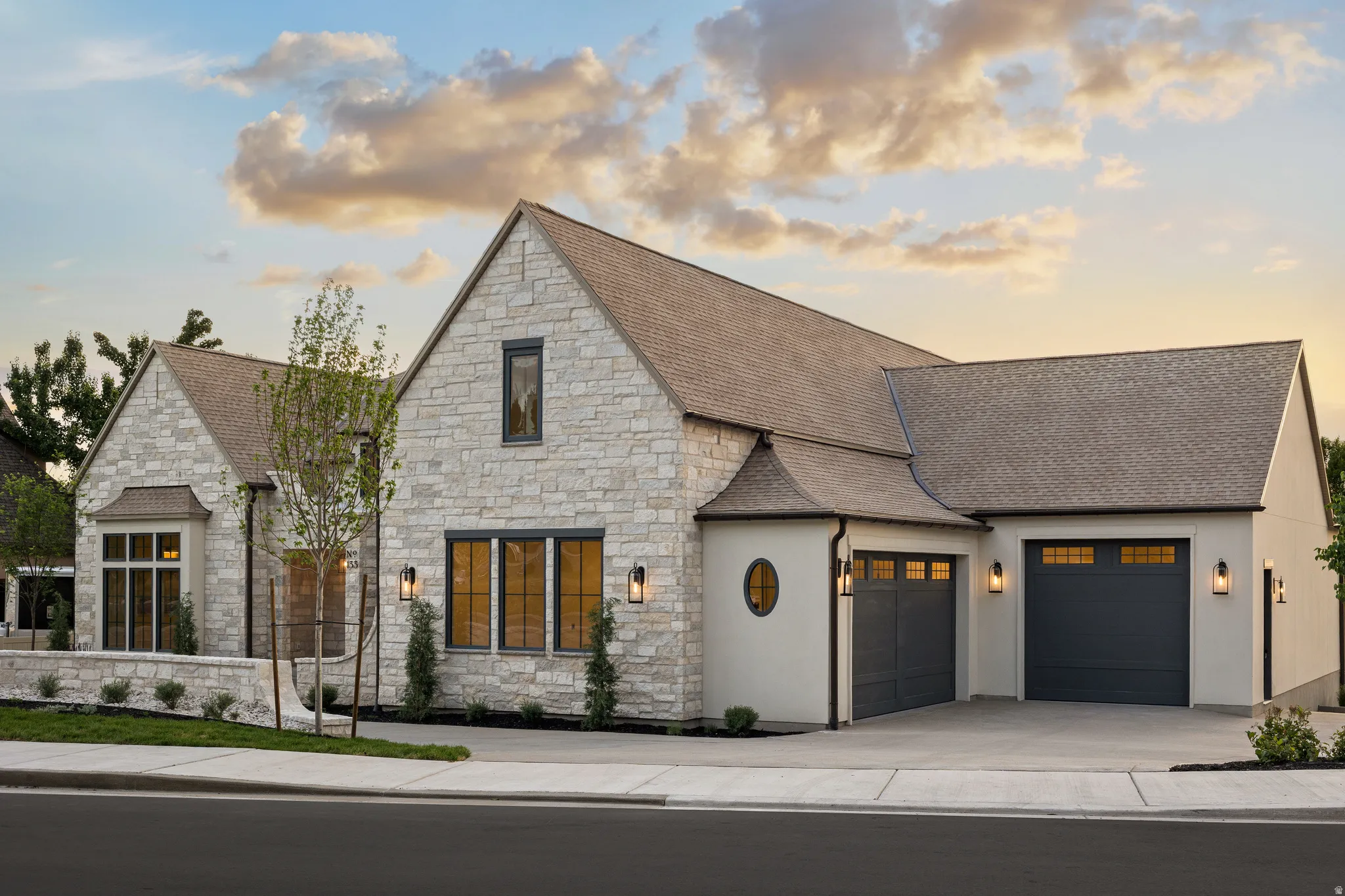 Stone and stucco exterior featuring multiple gables and a multi-car garage