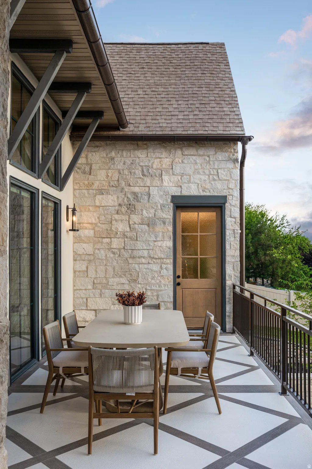 Spacious outdoor balcony featuring a stone exterior, decorative railing, and patterned flooring