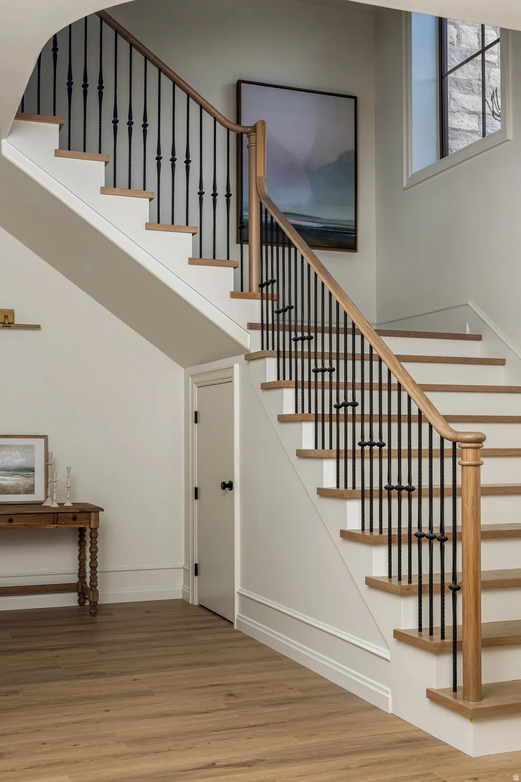 Staircase featuring wood-finish treads, painted risers, and a wrought iron baluster system with a wood handrail