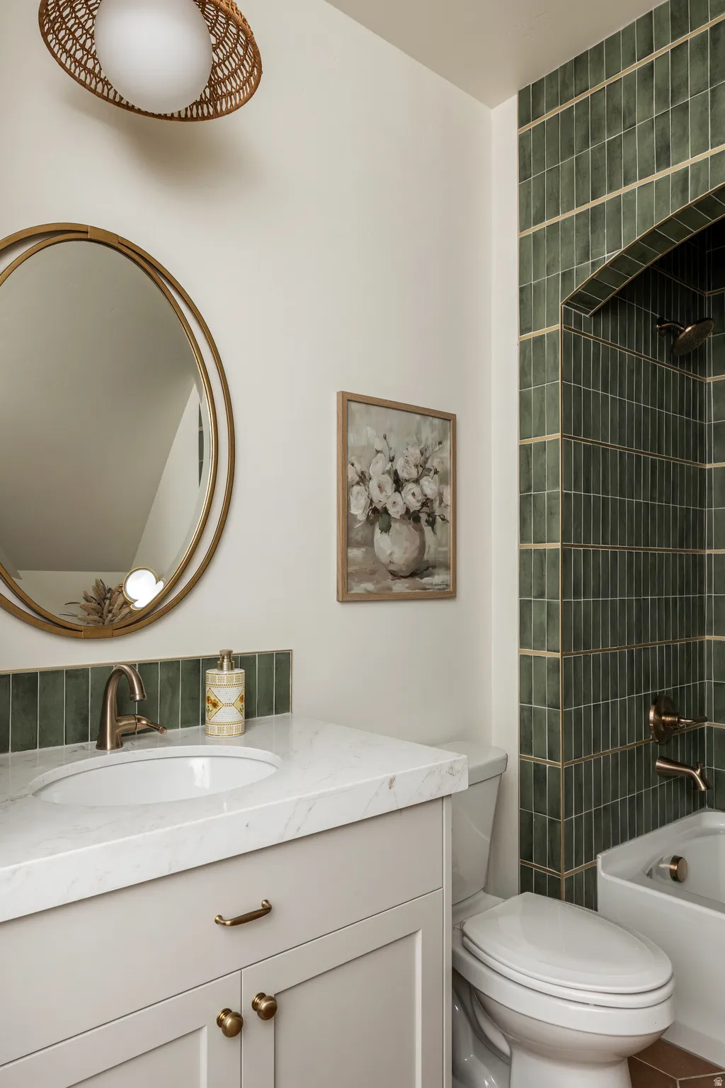 Bathroom vanity featuring a white oval undermount sink, a light-toned countertop, and a brass-finish faucet