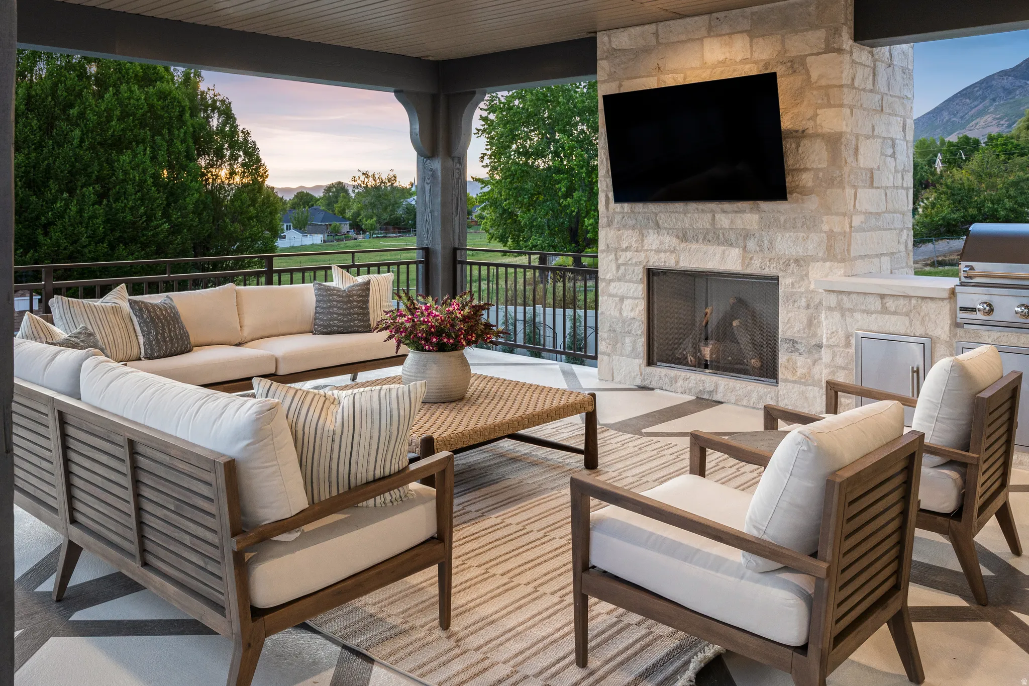 Covered outdoor patio featuring a stone fireplace, built-in outdoor grill, and patterned concrete flooring