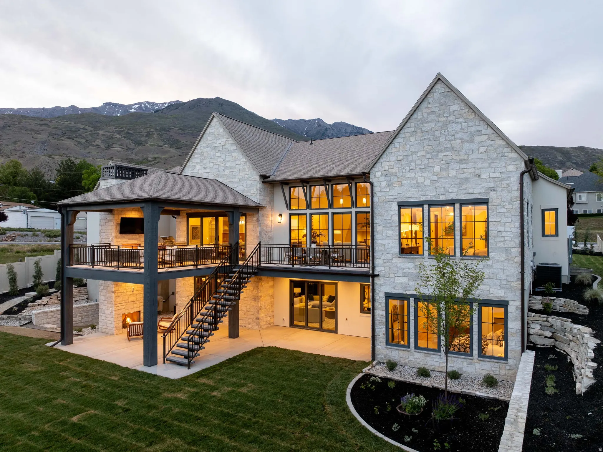 Stone exterior residence featuring a covered upper-level patio with an outdoor fireplace and television