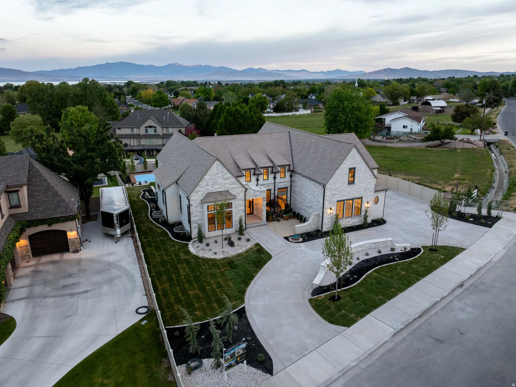 Stone exterior residence featuring a multi-gabled roofline and an expansive, curved concrete driveway