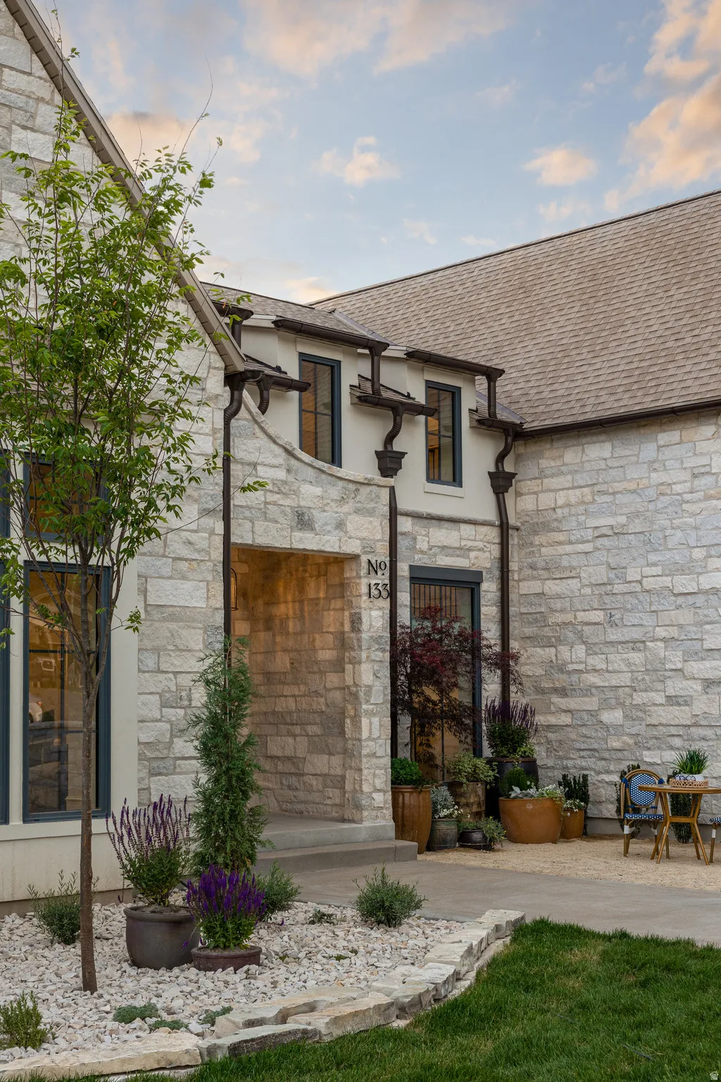 Stone exterior with dark trim windows and a natural landscaping design