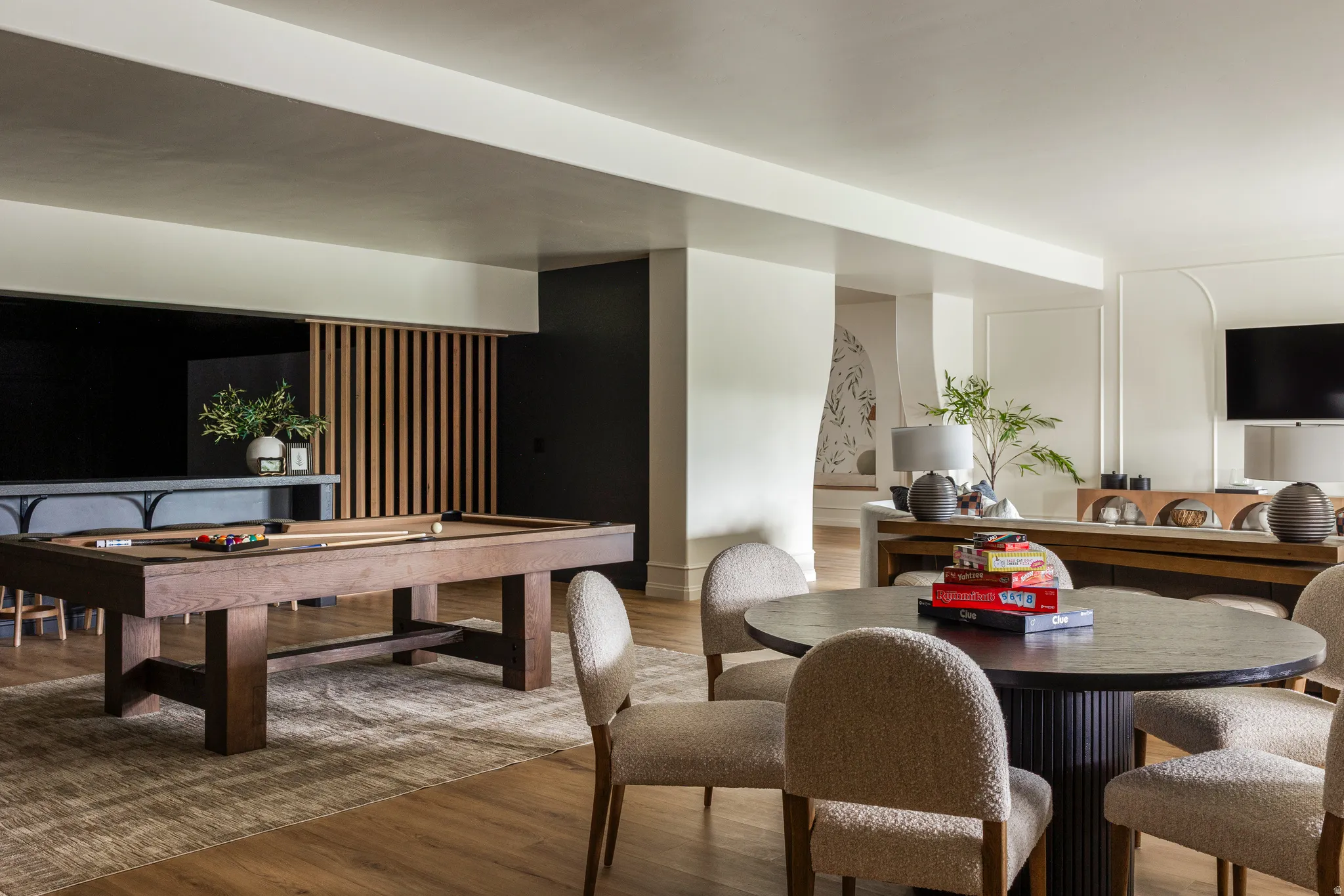 Recreation room featuring wide plank wood-finish flooring, a built-in bar with dark cabinetry, and a slatted wood accent wall