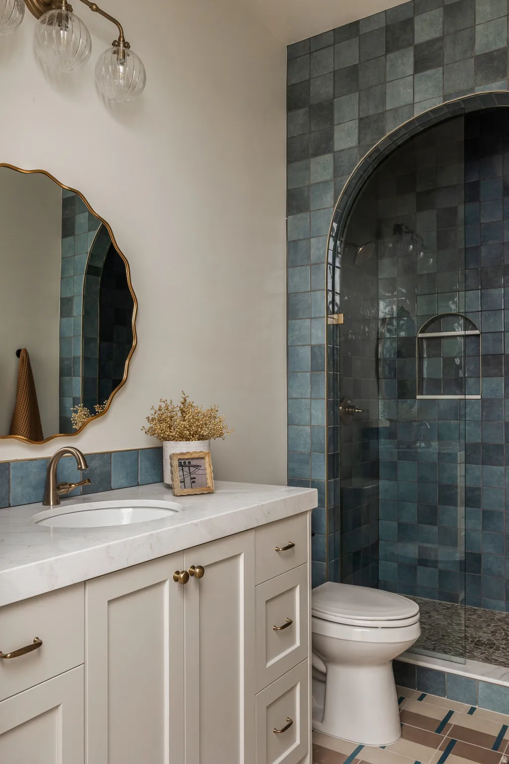 Bathroom featuring a walk-in shower with an arched glass enclosure, blue tile surround, and a built-in shower niche