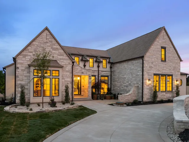 Stone exterior with gabled rooflines, dark-framed windows, and a curved driveway