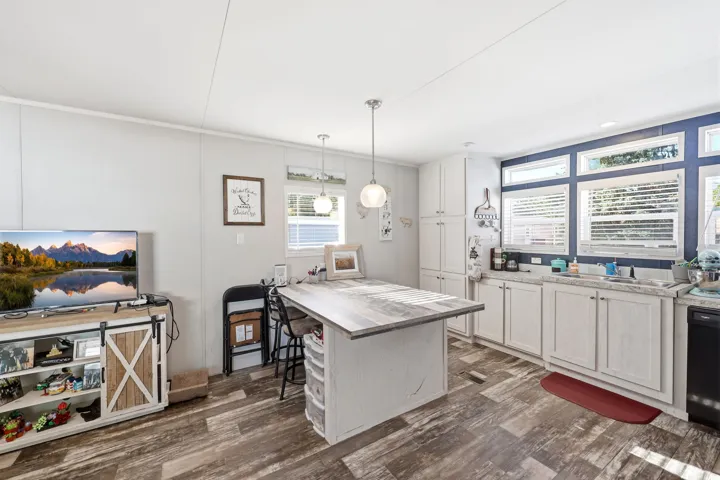 Kitchen area featuring white cabinetry, light countertops, and a wood-finish island with seating