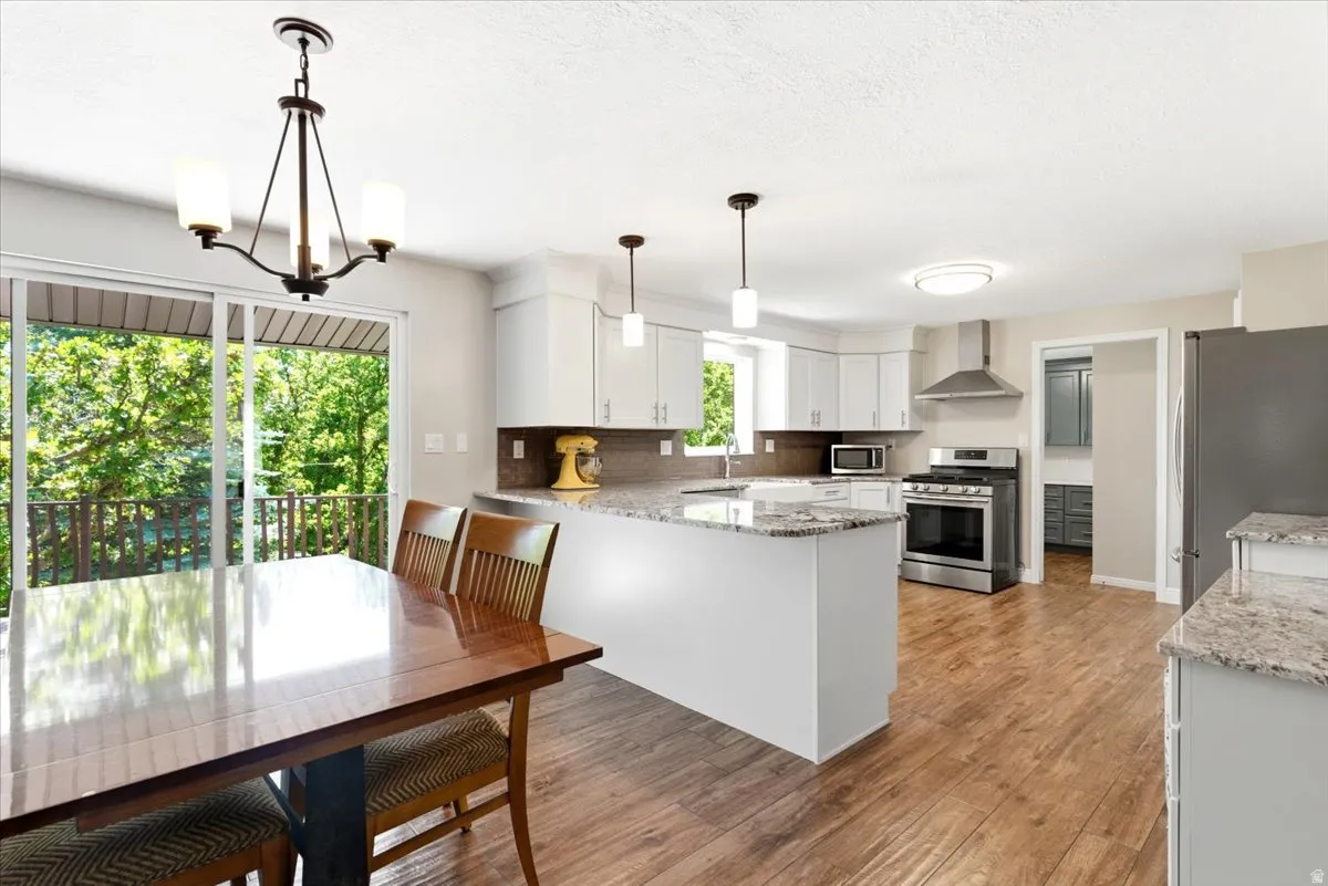 Updated kitchen with beautiful granite countertops, white shaker cabinets, 5 burner gas range, large basin farmhouse sink, & glass tile backsplash